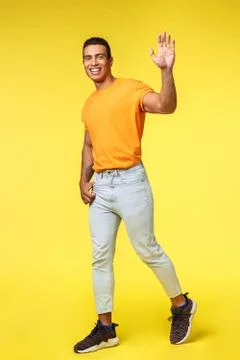 Vertical full-length studio shot friendly young handsome man smiling, waving Fotos Stock