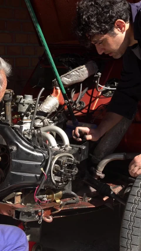 Vertical Garage setup showcasing teamwork repairing vintage motor components Stock Footage 313230120