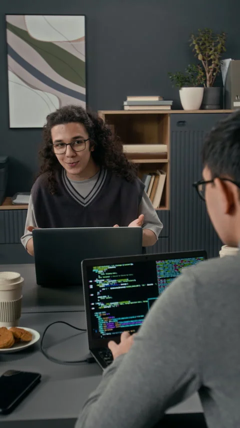 Vertical of Gen Z Developer Explaining Viewpoint to Coworker Coding on Laptop Video stock 329617653