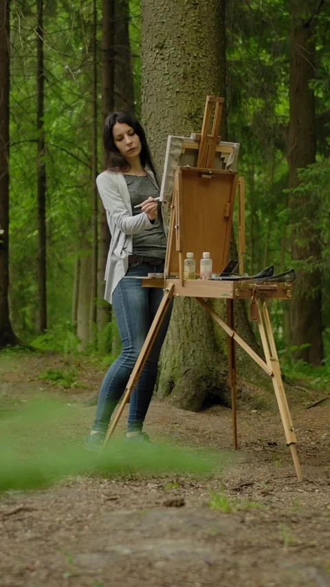 Vertical of General wide shot of a cute artist painting a landscape on an easel Stock Footage 276919799