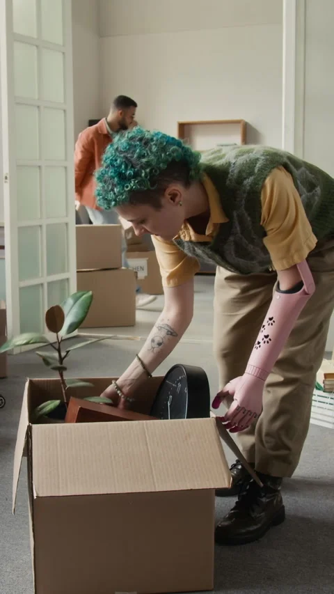 Vertical of Girl with Bionic Arm Unpacking Moving Box after Relocating 스톡 동영상 323296880