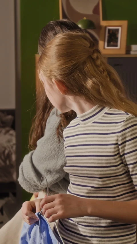 Vertical of Girl Child Comparing Clothes with Mom while Getting Dressed at Home Stock Footage 334342355