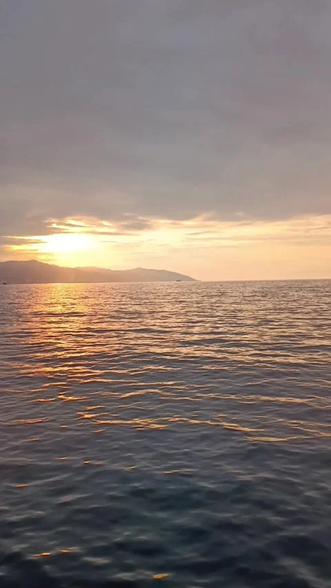 Vertical Golden Hour Sea Waves with Sun Reflection and Mountains Stock Footage 344013591