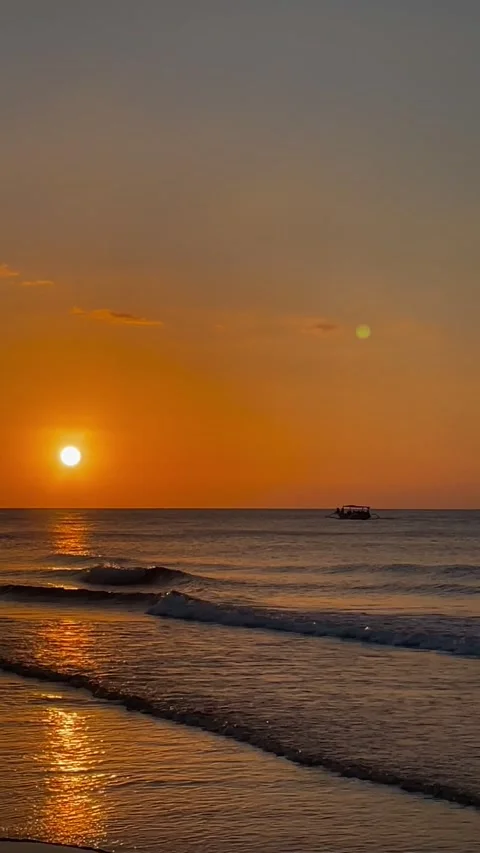 Vertical golden hour sunset over Bali beach with a silhouette boat Stock Footage 337857794