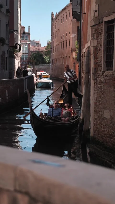 Vertical of Gondolier and tourists sail through the canal in Venice Stock Footage 278479727