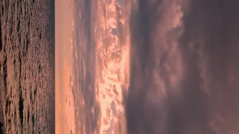 Vertical. Gray Black Storm Clouds Orange Peach Sky in Sunlight Ocean Waves Slow  Stock-Footage 297390823