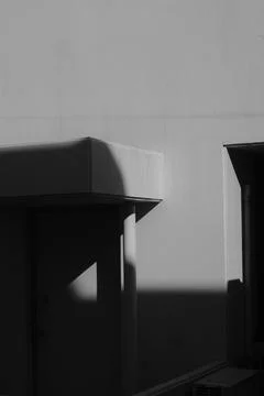 A vertical grayscale shot of a wall with a protuberance partially under the s Stock Photos