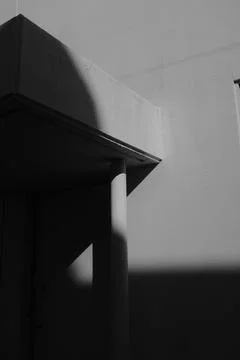 A vertical grayscale shot of a wall with a protuberance partially under the s Stock Photos