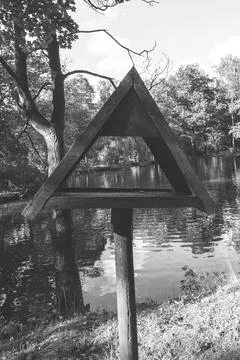 A vertical grayscale of a triangle figure on the top of a post standing near  Stock Photos