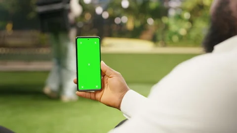 Vertical green screen isolated mockup on smartphone held against city park Stock Footage 343501116