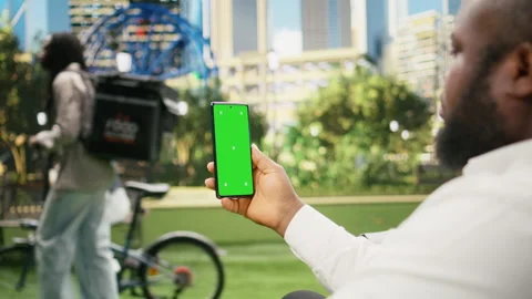 Vertical green screen isolated mockup on smartphone held against city park Stock Footage 343506934