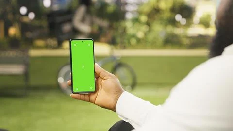 Vertical green screen isolated mockup on smartphone held against city park Foto stock