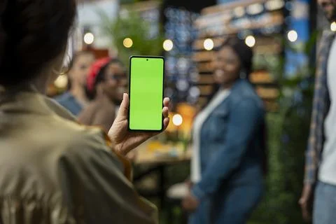 Vertical green screen on mobile phone in front of friends at social gathering Stock Photos