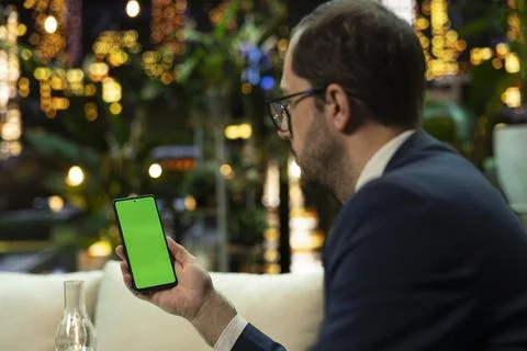 Vertical green screen on smartphone held by businessman at night Foto stock