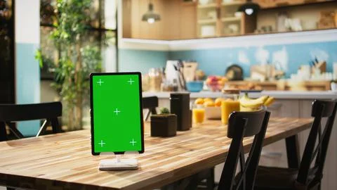 Vertical green screen on tablet in empty wooden stylish kitchen space Stock Photos