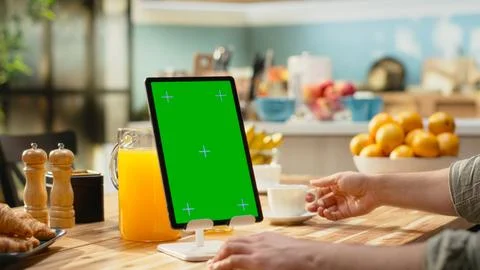 Vertical green screen on tablet with man sitting at wooden table Stock Photos