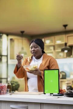 Vertical green screen tablet next to black woman recording food content vlog Stock Photos