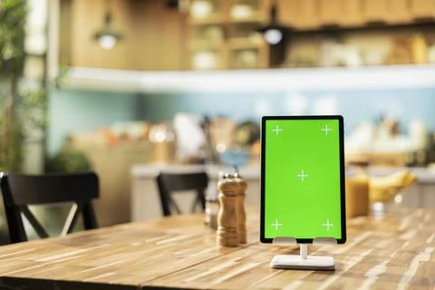 Vertical green screen tablet placed on empty table in rustic kitchen space Stock Photos