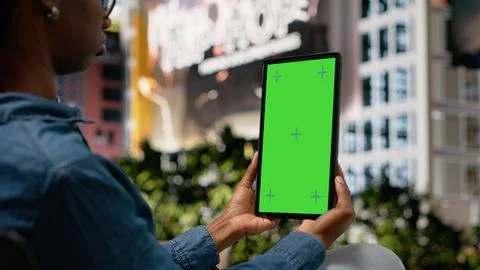Vertical green screen tablet used by person to watch movies, sitting on bench Stock Photos