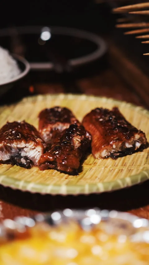Vertical grilled fish pieces with glaze served on woven plate in restaurant Video stock 333879226