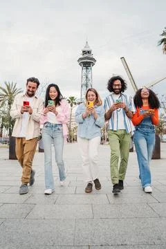 Vertical. Group of smiling multiracial young people using their mobile phones Stock Photos
