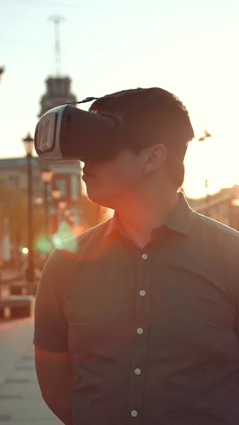 Vertical of Guy in vr glasses in city. Sunset or sunrise Stock Footage 278475307