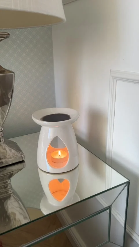 Vertical hand lighting tealight in ceramic wax burner on mirrored nightstand Stock Footage 346486336