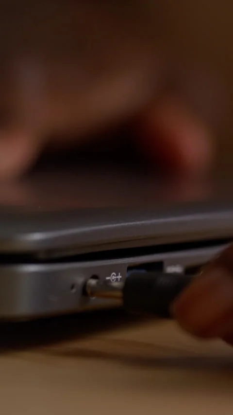 Vertical of Hand Plugging Electric Power Cable into Socket on Laptop Stock Footage 317974395
