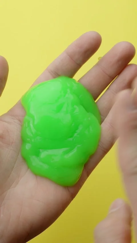 Vertical hand pressing soft green slime against palm with yellow background Stock-Footage 313597388
