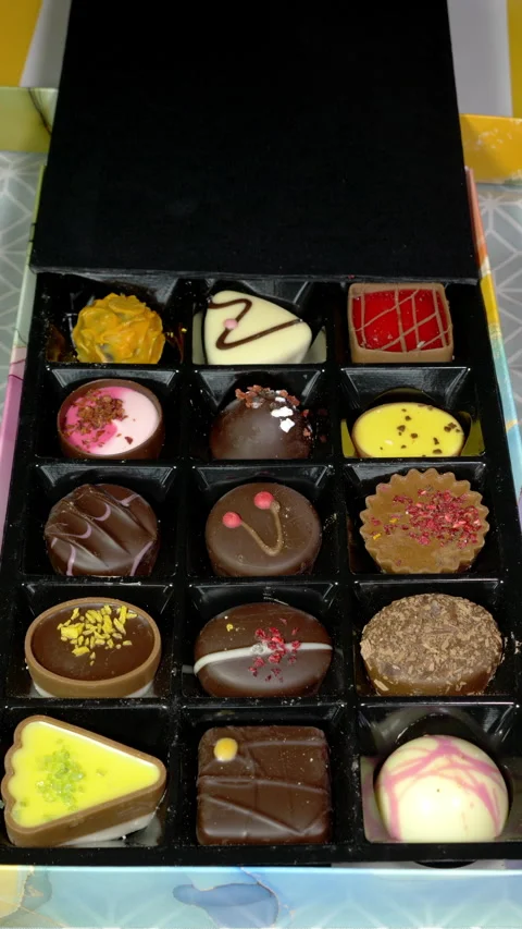 Vertical - A hand pulling the cover from a colorful selection box of chocolates. Stock Footage 280228824