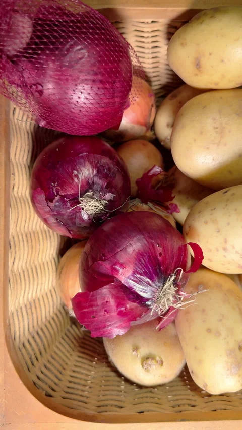 Vertical - A hand squeezing red onions from a mesh bag into a vegetable basket. Stock Footage 301733312