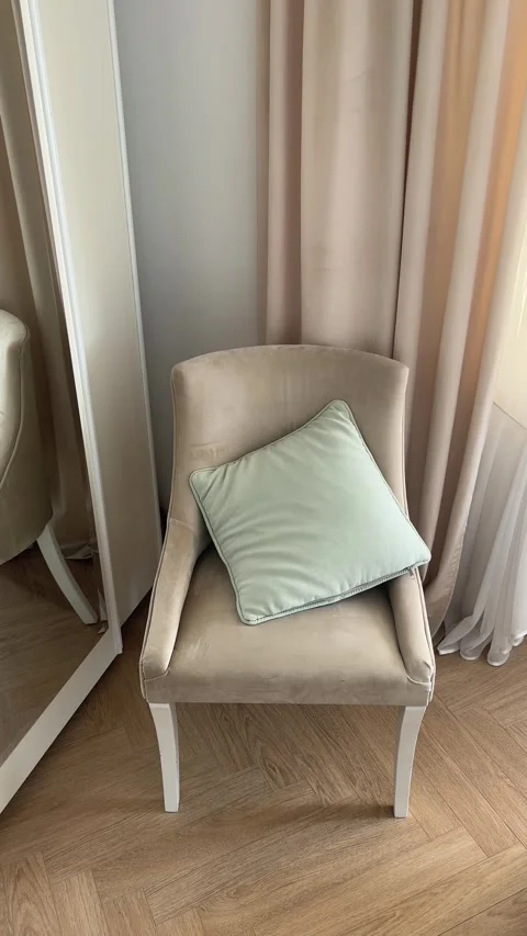 Vertical hand throwing mint green cushion onto beige velvet armchair in room Stock Footage 346486653