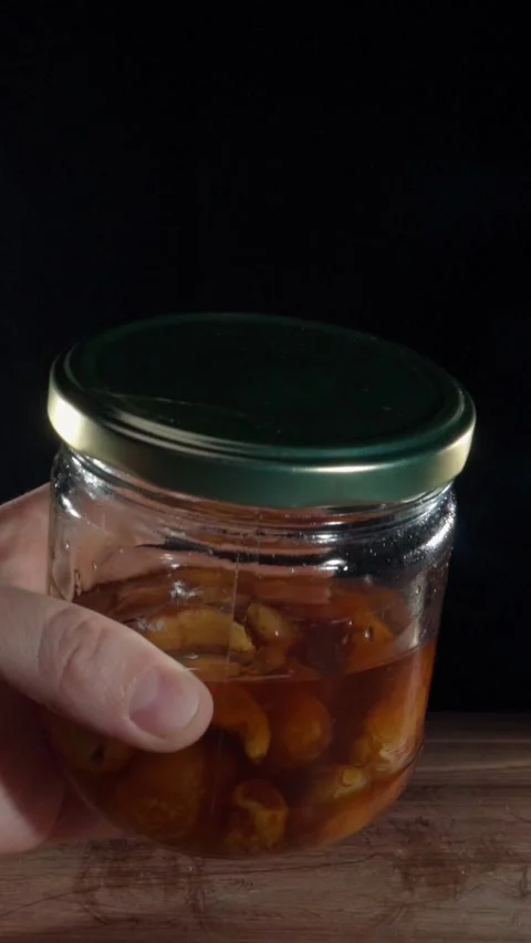 Vertical Hand Tilting Fermented Garlic Honey Jar Showing Viscosity Slow Motion Stock Footage 324921942