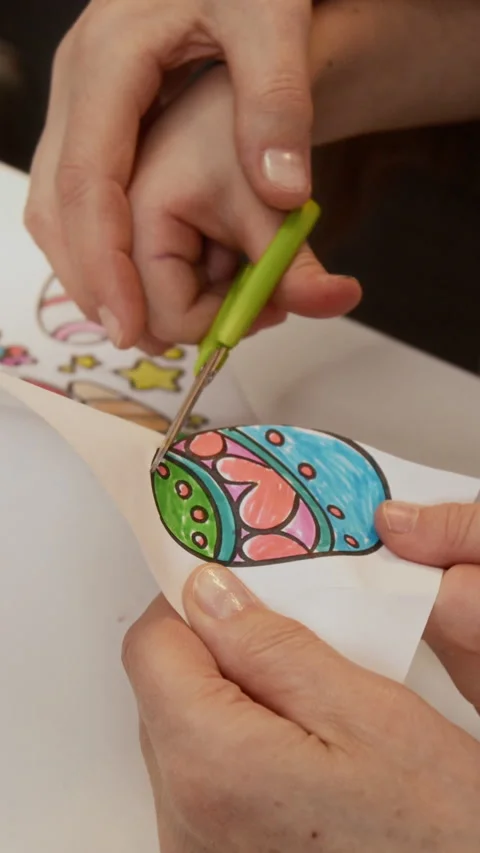 Vertical of Hands of Adult Helping Little Kid to Cut Out Easter Egg Drawing Stock Footage 327888990