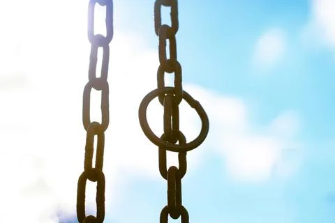 Vertical hanging rusty chain. Sunlight, blue background. For text area Stock Photos