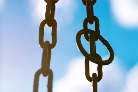 Vertical hanging rusty chain. Sunlight, blue background. For text area Stock Photos