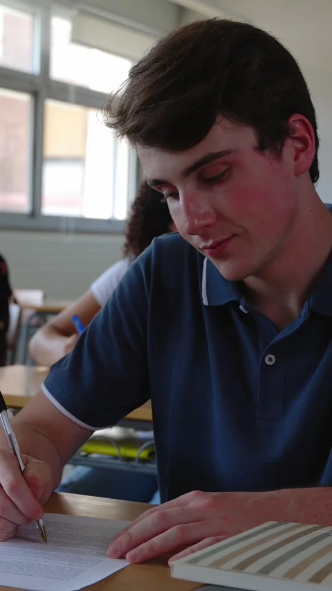 Vertical HD video of young student man doing an exam at high school classroom Stock Footage 312201012