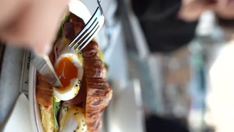 Vertical : He cuts the egg inside the croissant with a knife Video stock 196177180