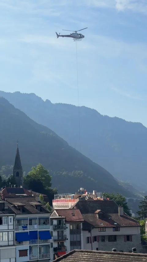Vertical Helicopter Lifting Cargo Over Swiss Alpine Village 스톡 동영상 337931516