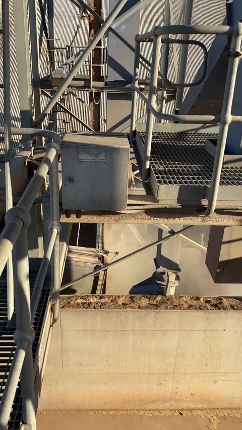 Vertical High-Angle Shot of Grain Being Loaded from a Silo Spout into a Railway Stock Footage 344772560