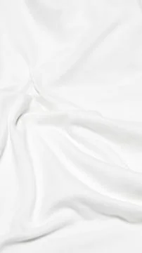 A vertical, high angle shot of a white fabric surface characterized by soft,  Stock Photos