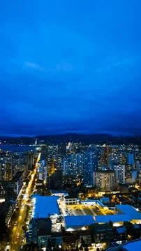 Vertical high angle view of an illuminated modern city skyline at dusk with d Stock Photos