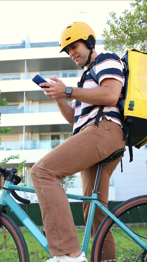 Vertical Hispanic delivery man on bicycle checking smartphone for directions Stock Footage 318096156