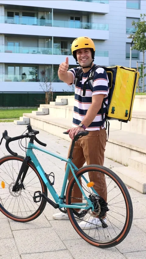 Vertical Hispanic food delivery man posing with bicycle and giving thumbs up Stock Footage 318096151