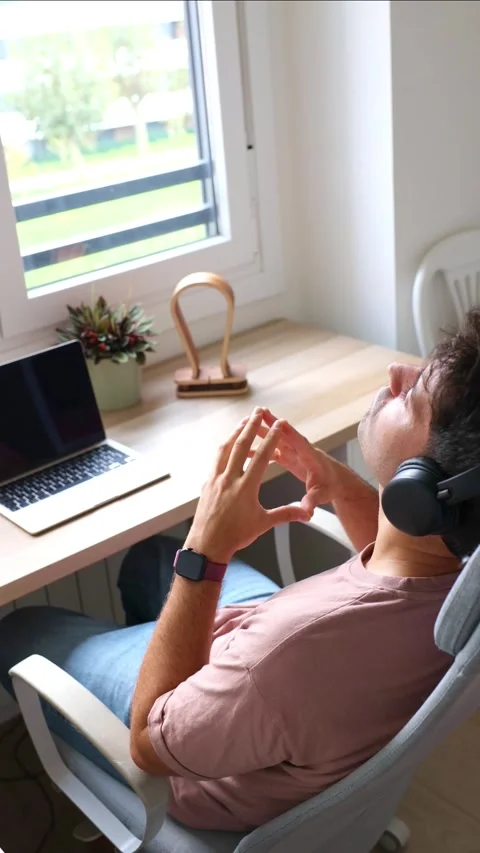 Vertical Hispanic man relaxing and teleworking with headphones at his home .. Stock Footage 319027707