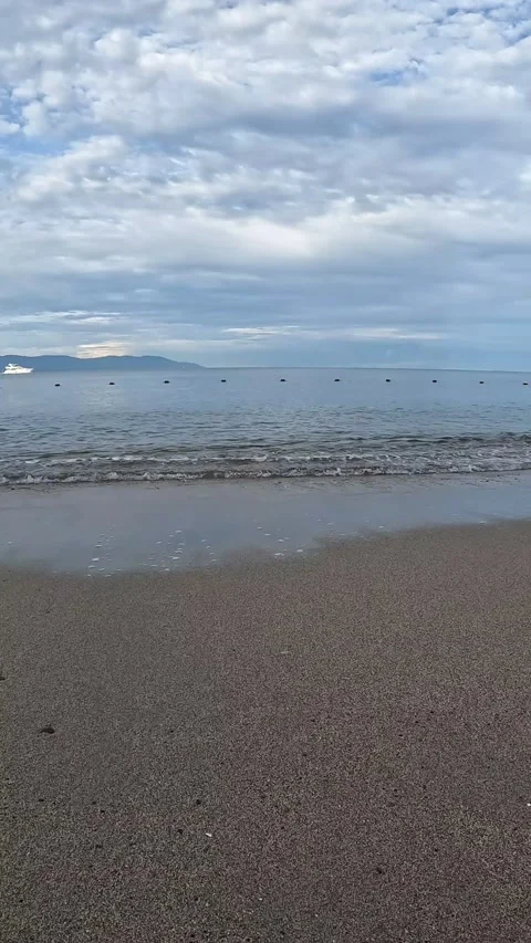 Vertical image of beach with waves and yacht in the background Stock Footage 215011908