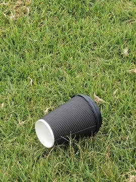 Vertical image of a black takeaway cup thrown in the floor Foto stock