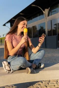 Vertical image, cheerful lady sitting outdoors chatting with mobile phone a.. Stock Photos