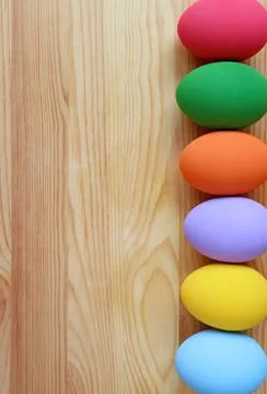Vertical Image of Colorful Easter Eggs in Row on Wooden Background Stock Photos