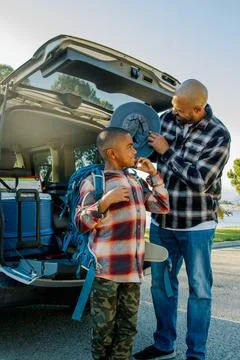 Vertical image of dad and son smiling whilte putting on hat and unloading the Stock Photos